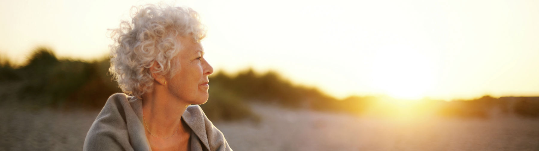 elderly senior-woman-on-beach-looking-into-horizon-cropped