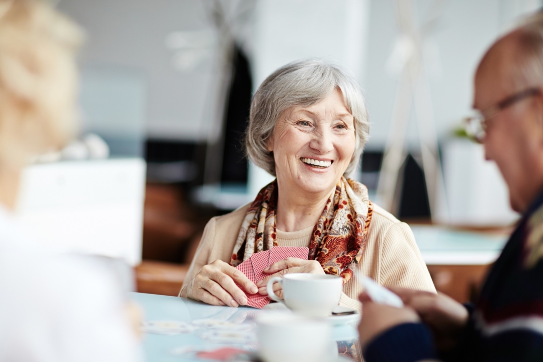 Senior people playing cards grandma elderly woman with her friends in assisted living memory care